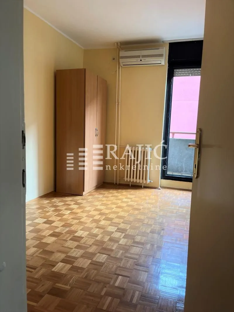 Furnished bedroom with a wardrobe and parquet flooring.
