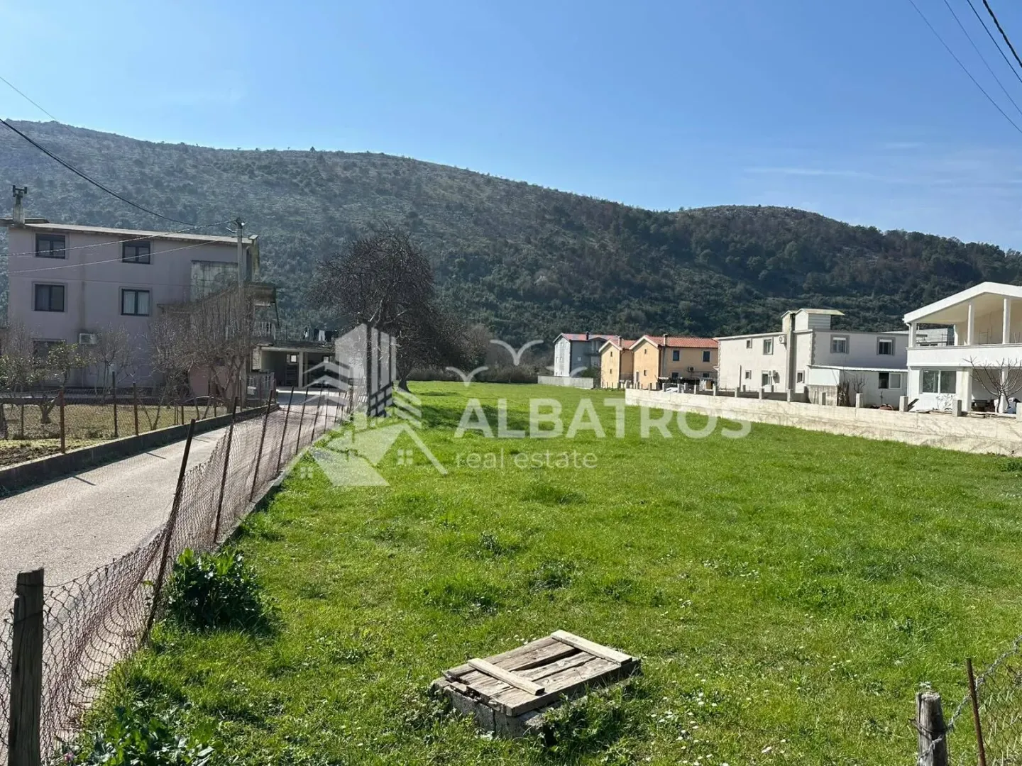 Pogled na plac sa travnjakom i okolnim kućama.
