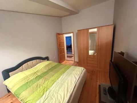 Spavaća soba sa velikim bračnim krevetom, drvenim ormarom i televizorom. - image 5