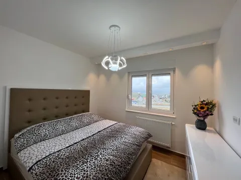 Uređena spavaća soba sa bračnim krevetom, modernim lusterom i prozorom sa pogledom. - image 8