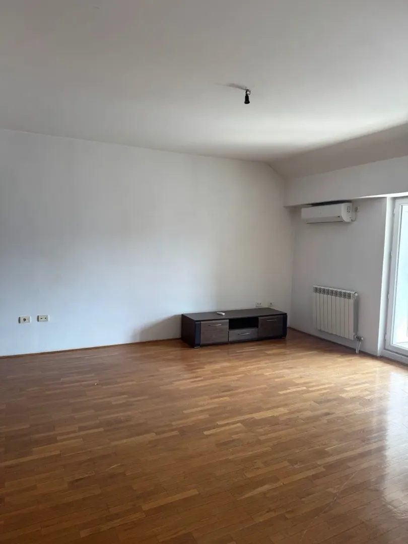 Empty living room with parquet flooring and an air conditioner.
