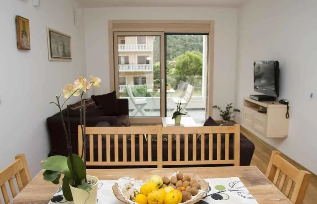 Svijetao dnevni boravak sa trpezarijskim stolom u prvom planu i izlazom na balkon.