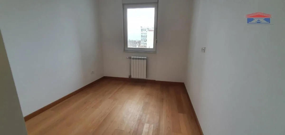 Empty room with hardwood flooring and a single window.
