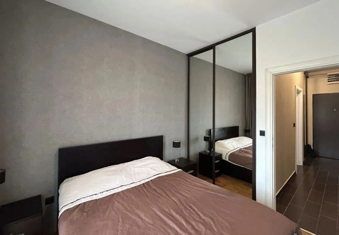 Furnished bedroom with a double bed, mirrored wardrobe, and a view of the hallway.