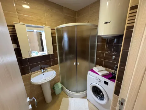 Bathroom with a shower cabin, sink, and washing machine. - image 12