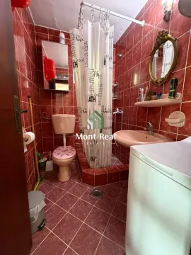 Manje kupatilo obloženo crvenim pločicama sa tuš kabinom i veš mašinom. - image 14