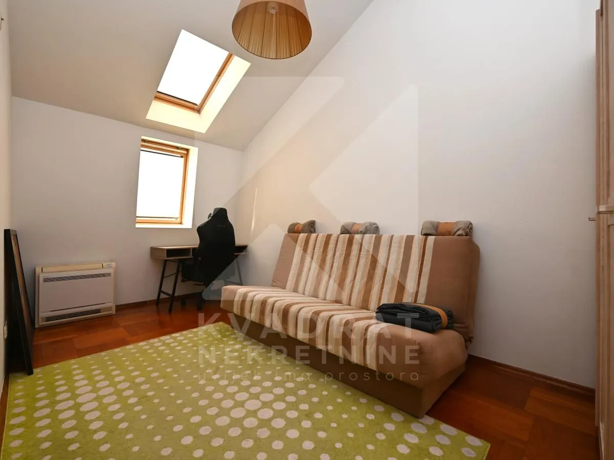 Smaller room with a sofa, desk, and roof window.