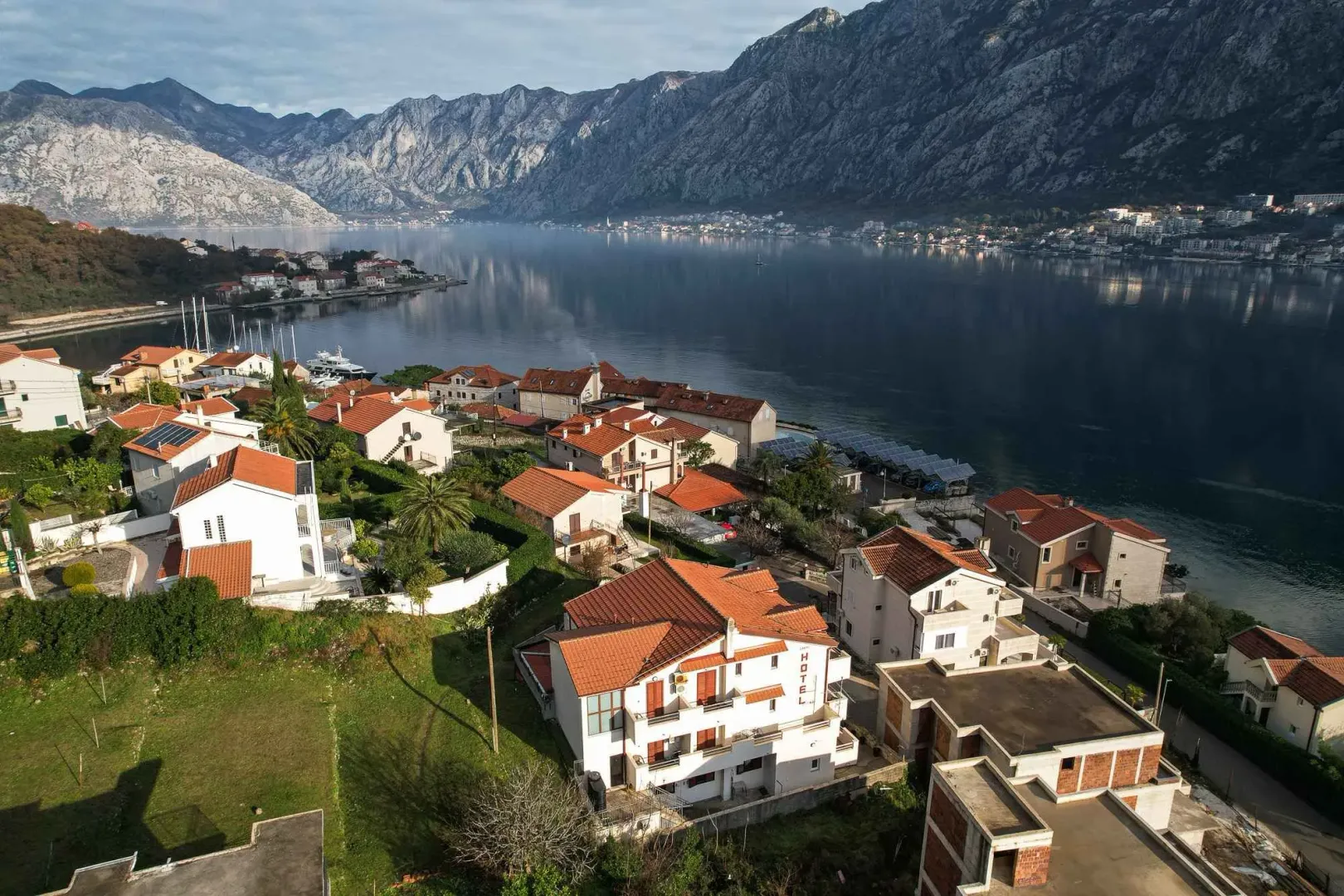 Pogled iz vazduha na obalu sa kućama i planinama u pozadini.