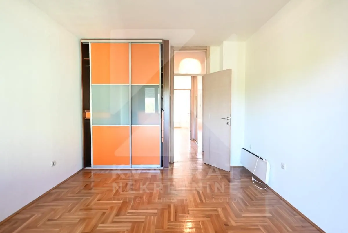 Empty room with parquet flooring and a built-in wardrobe with orange sliding doors.