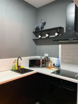 Modern dark-toned kitchen with white countertops and built-in appliances. - image 3