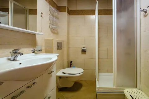 Small bathroom with a sink, toilet, and shower cabin tiled in beige. - image 18
