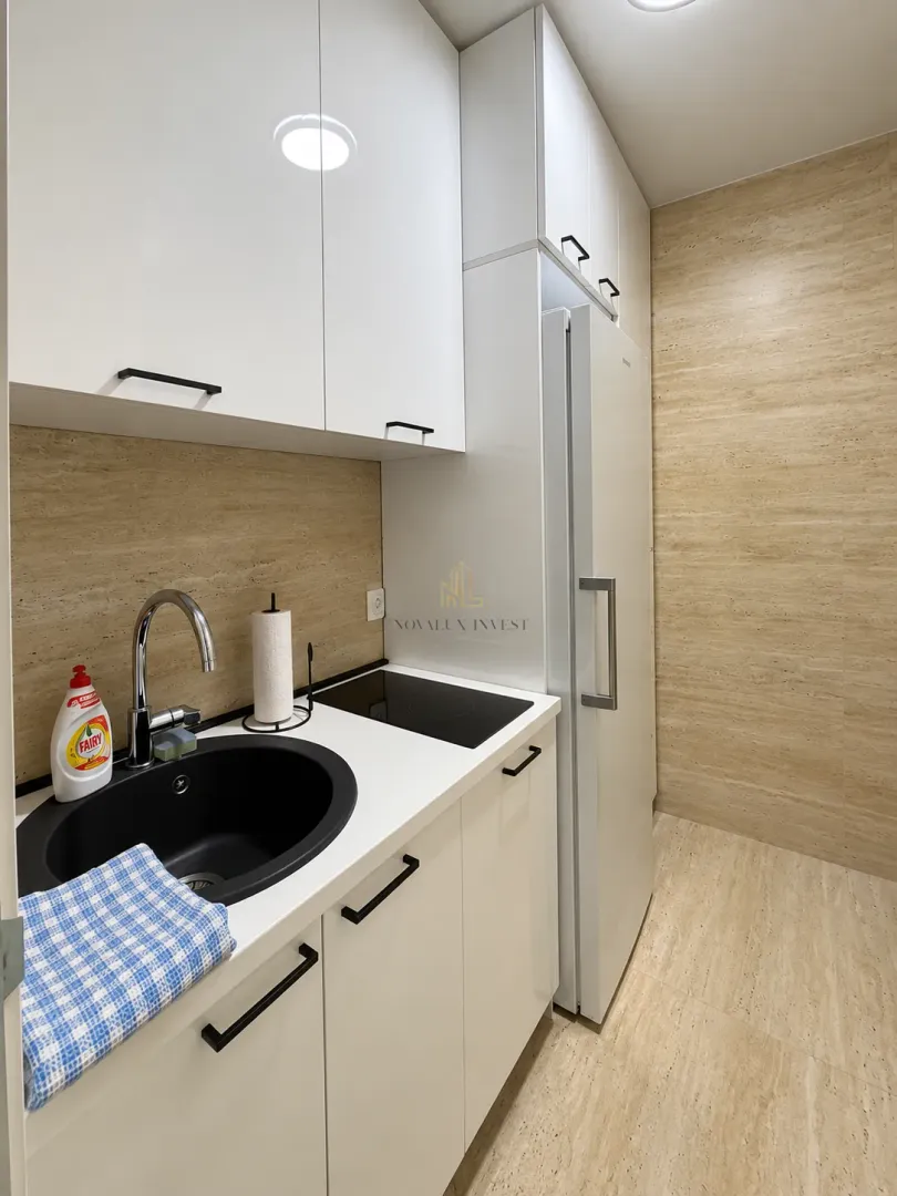 Small white kitchen with a sink, built-in cooktop, and refrigerator.