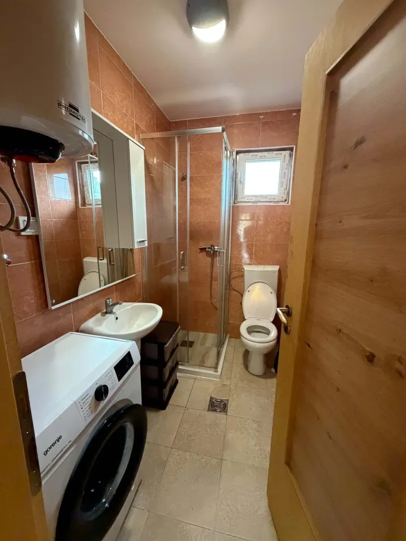 Bathroom equipped with a shower cabin, sink, toilet, and washing machine.