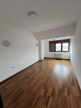 An empty room with wooden flooring, white walls, and a window. - image 10