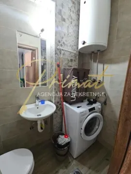 Smaller bathroom with a sink, toilet, washing machine, and water heater. - image 8