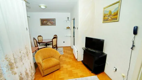 Dnevna soba sa foteljom, TV-om i trpezarijskim stolom u pozadini. - image 5