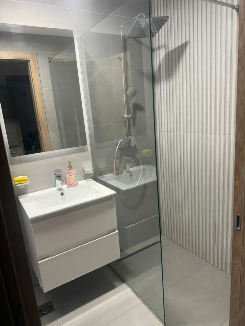 Bright and modern bathroom with a walk-in shower and a white vanity unit.