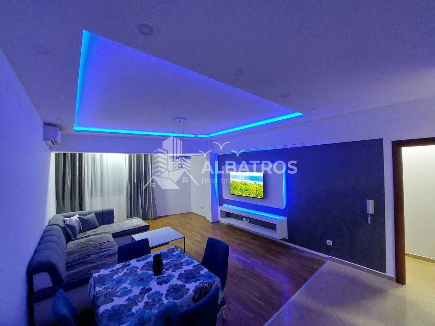 Living room with a sofa, dining table, and blue ceiling lighting.