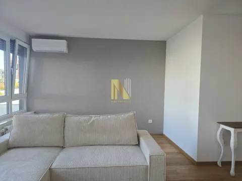 Dnevna soba sa bež ugaonom garniturom i klima uređajem na zidu. - image 4