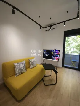 Dnevna soba sa žutim kaučem, televizorom i izlazom na terasu. - image 2