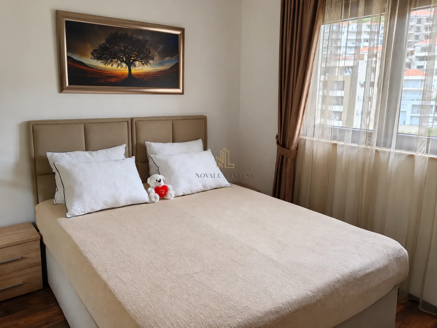 Furnished bedroom with a double bed, bedside tables, and a window with curtains.