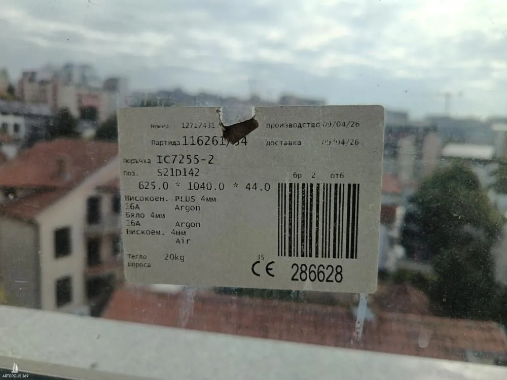 Nalepnica sa specifikacijama prozora zaliepljena na staklo sa pogledom na grad.