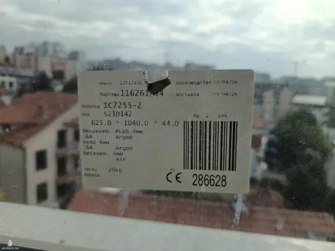 Nalepnica sa specifikacijama prozora zaliepljena na staklo sa pogledom na grad. - image 13