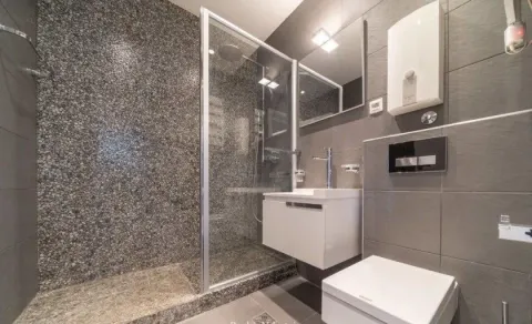 Modernly equipped bathroom with a shower cabin and grey tiles. - image 6