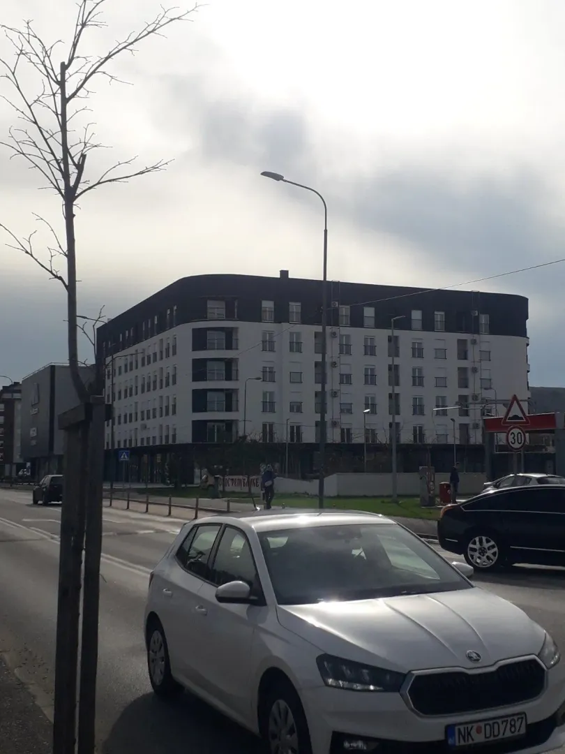Moderna stambena zgrada uz ulicu sa automobilima u prvom planu.