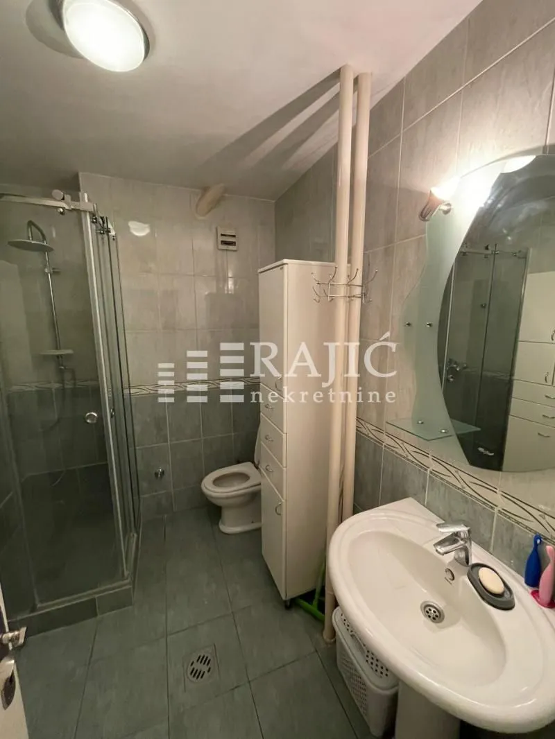 Small tiled bathroom with a shower cabin and a washbasin.