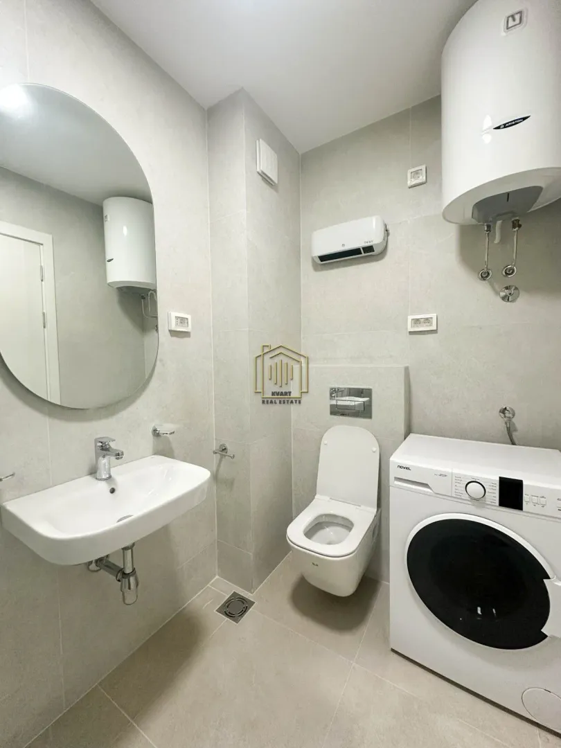 Moderno opremljeno kupatilo sa umivaonikom, WC šoljom i veš mašinom.