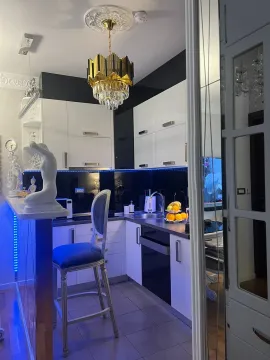 Moderna kuhinja sa bijelim elementima, šankom i dekorativnom rasvjetom. - image 15