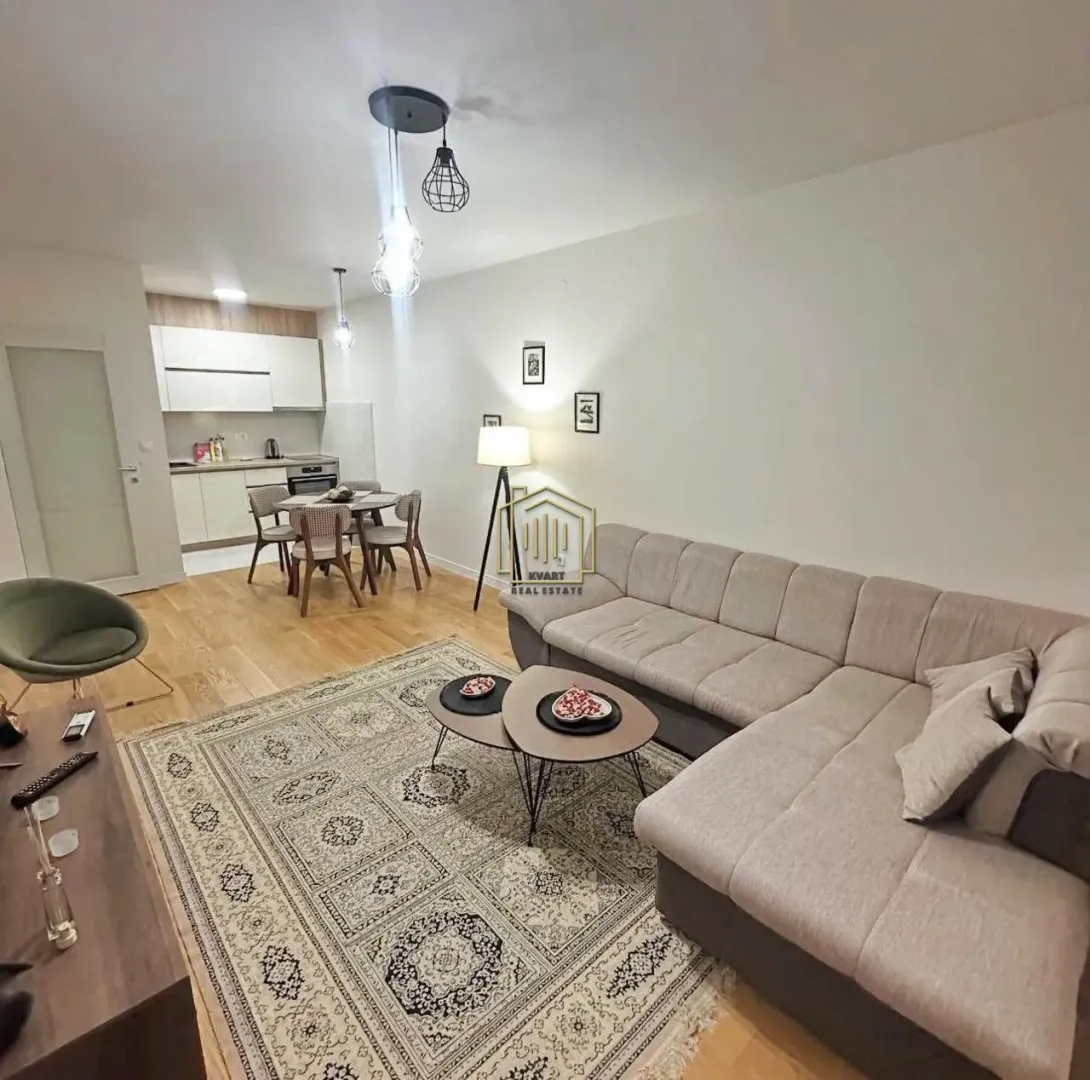 Living room with a sofa and a dining area in the background.