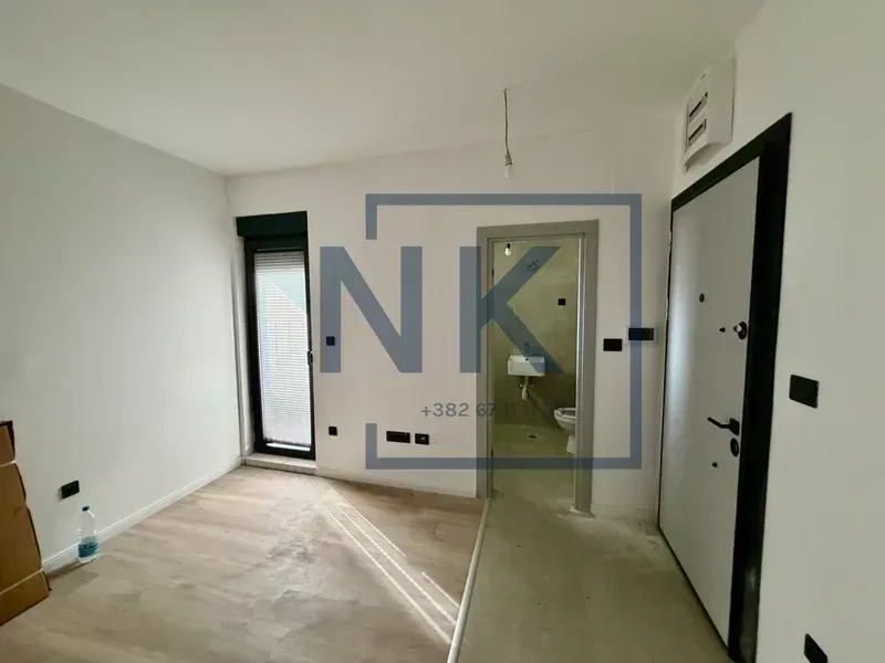 Prazna soba sa ulaznim vratima i pogledom na kupatilo u pozadini.