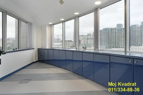 Modern kitchen with blue units and large windows offering a city view. - image 13