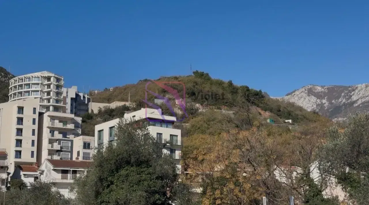 Pogled sa nekretnine na okolne zgrade, brda i planine.
