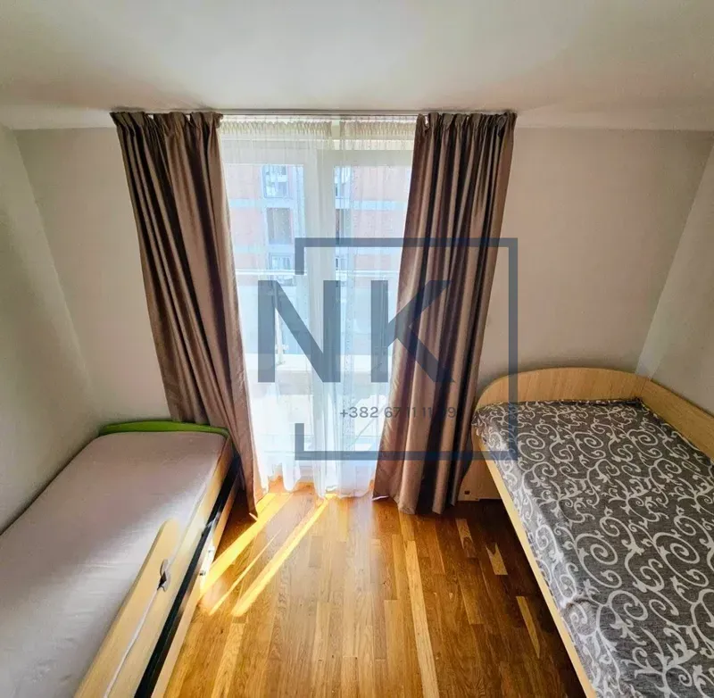 Children's bedroom with two single beds and balcony doors.