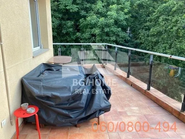 Prostrana terasa sa staklenom ogradom i pogledom na zelenilo.