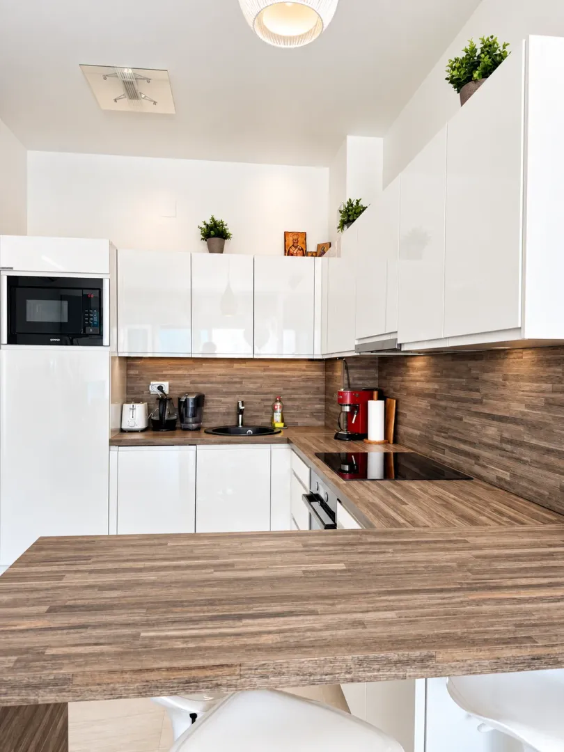Modern kitchen with white cabinets and a wooden countertop.