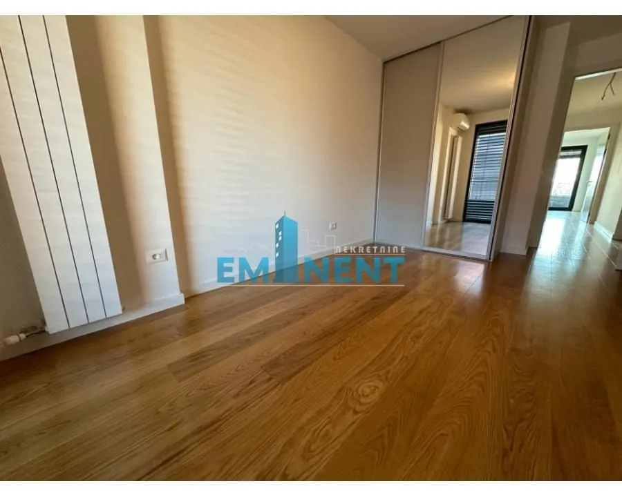 Empty bedroom with wooden flooring and a mirrored built-in wardrobe.