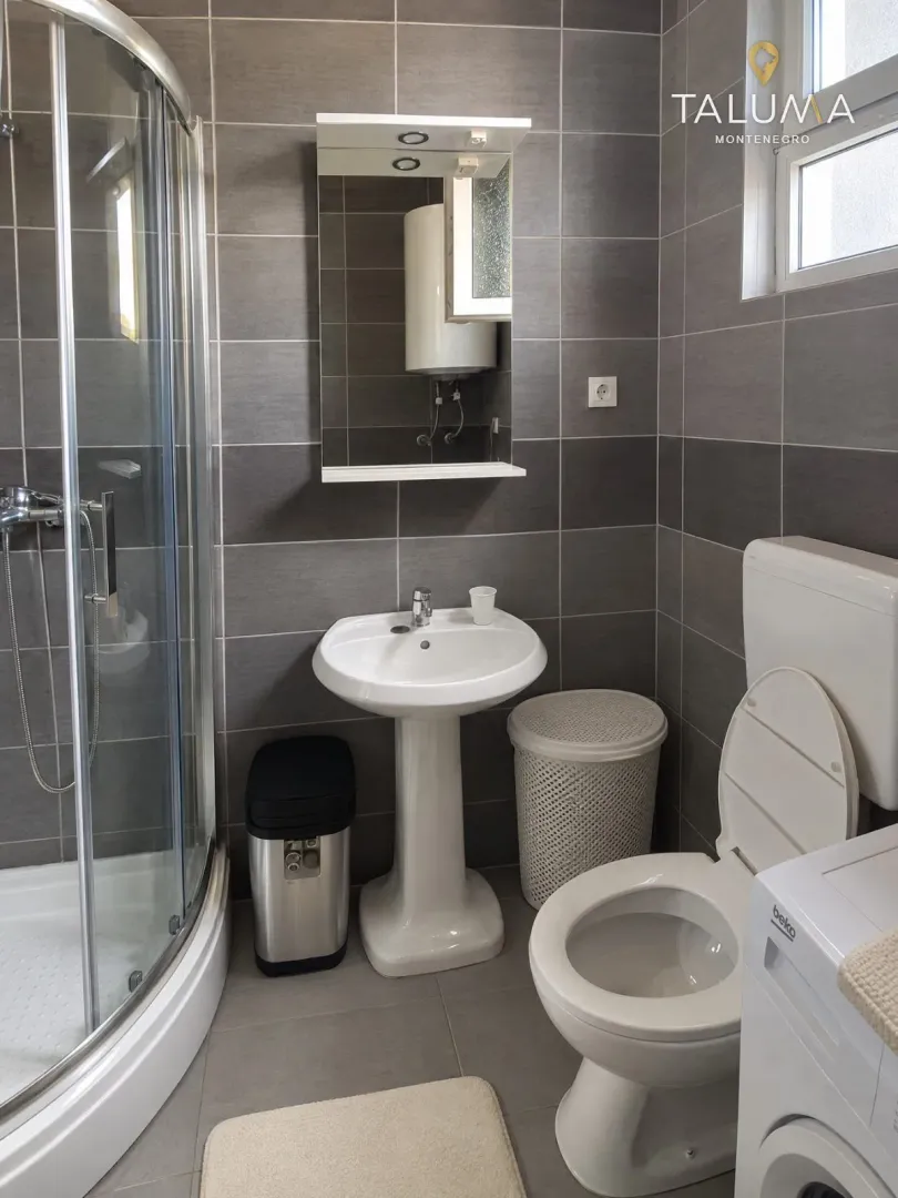 Bathroom with a shower cabin, washbasin, toilet, and a mirror.