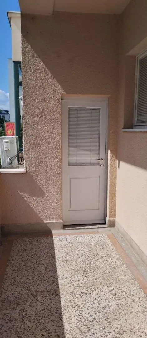 Dio terase sa bijelim ulaznim vratima i popločanim podom.