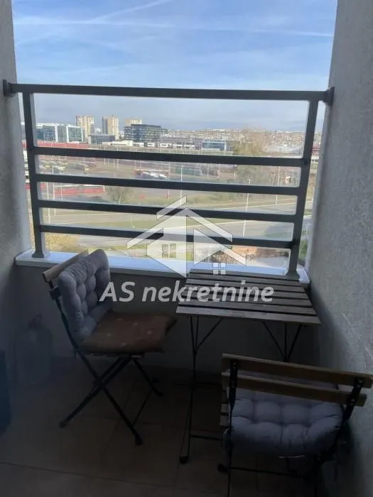 Manji namešteni balkon sa stolom i stolicama i pogledom na grad.