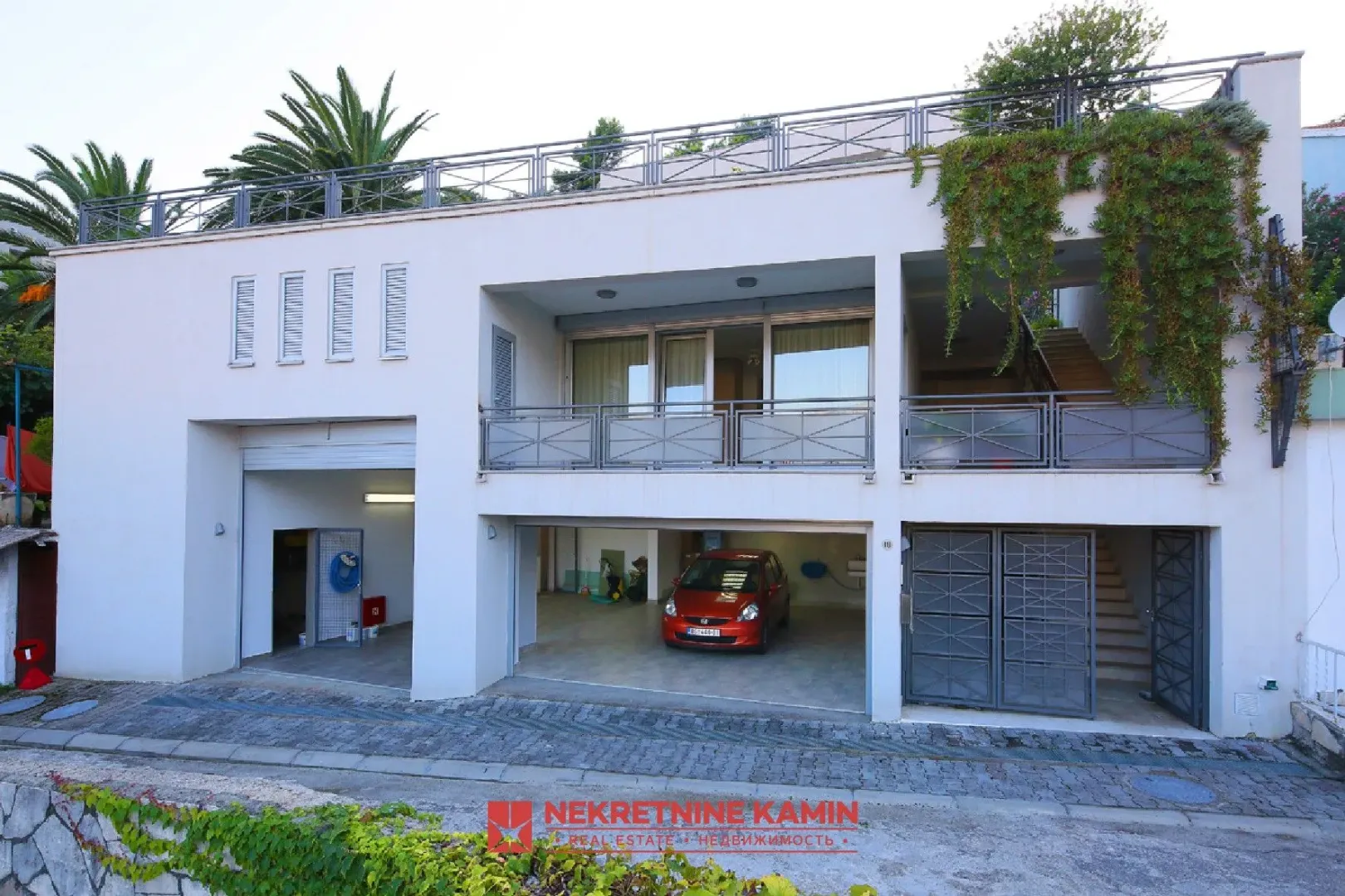 Front view of a two-story house with a ground-floor garage and upper-level terraces.