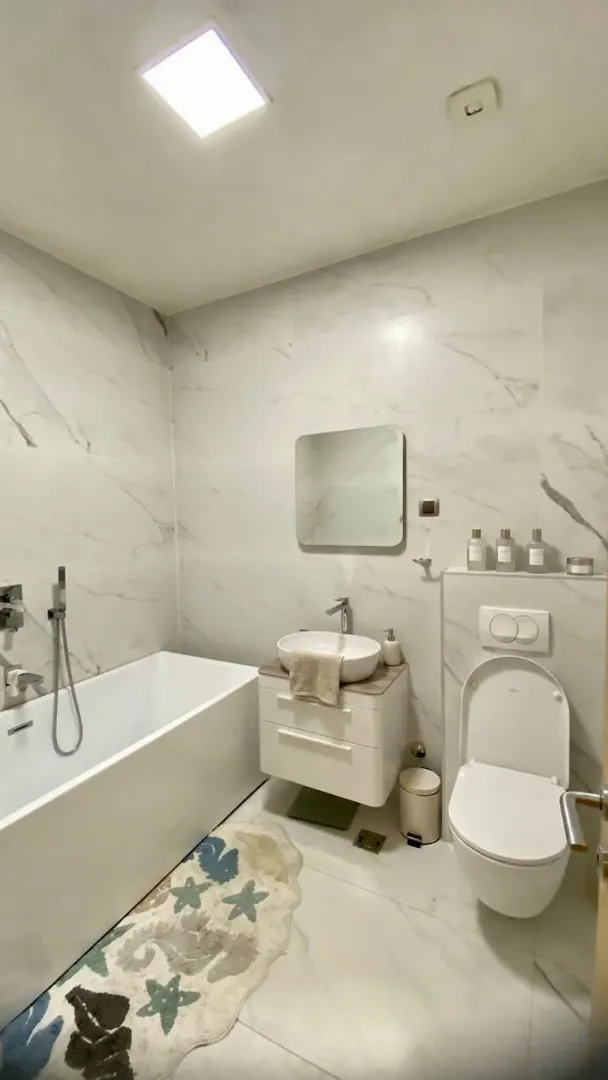 Modern bathroom equipped with a bathtub, washbasin, and toilet.