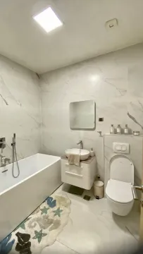 Modern bathroom equipped with a bathtub, washbasin, and toilet. - image 9