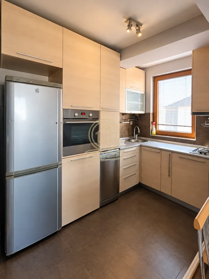 Kitchen with wooden cabinetry, built-in oven and refrigerator.