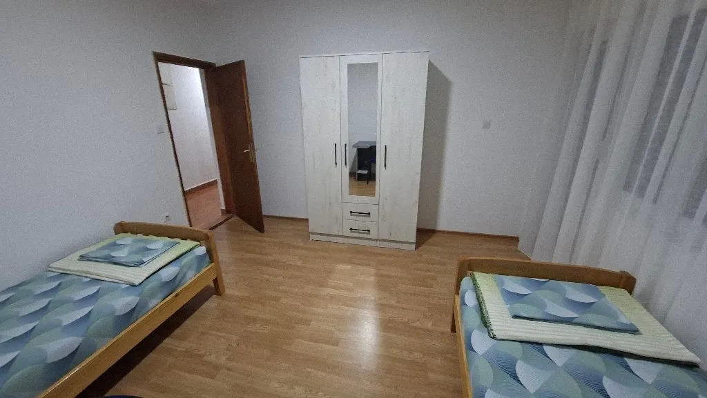 Spavaća soba sa dva kreveta i ormarom.