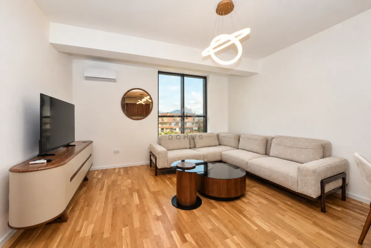 Spacious living room with a sectional sofa, TV unit, and wooden flooring.