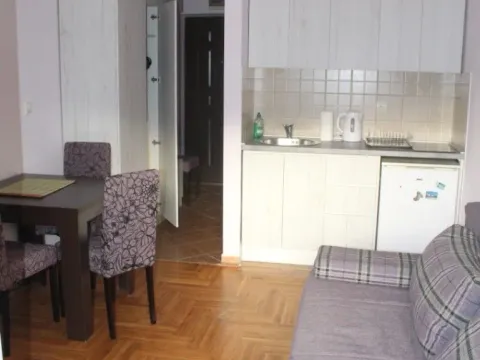 Living room with a sofa, dining table, and a small kitchen in the background. - image 3